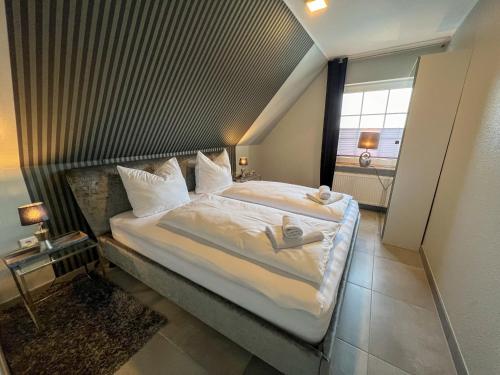 un grande letto in una piccola stanza con finestra di Huus am Meer a Norddeich