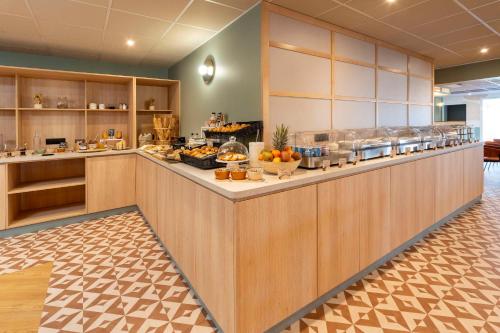 a cafeteria with a buffet line with food at Sure Hotel by Best Western Caen Memorial in Caen