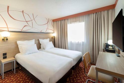カーンにあるSure Hotel by Best Western Caen Memorialのベッド2台と窓が備わるホテルルームです。