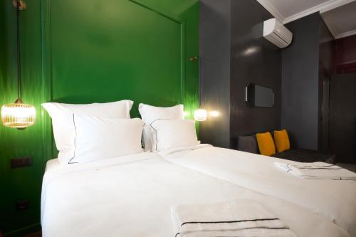 a bedroom with a large white bed with a green wall at Soho Athinas 60 in Athens