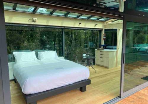 a master bedroom with a large bed and a balcony at Mākoha PurePod in Kerikeri
