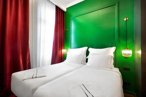 a bedroom with a large white bed with green walls at SoHo Athinas 60 in Athens