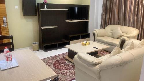 un soggiorno con 2 sedie e un tavolo di SADARA HOTELS APARTMENTS a Sohar