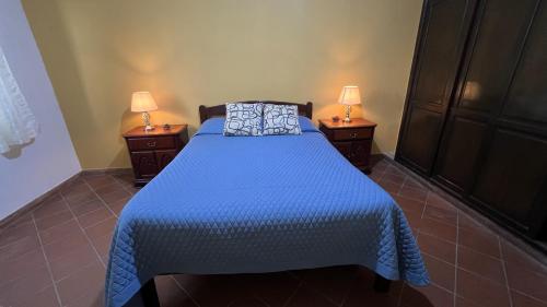 a bedroom with a bed with a blue comforter and two lamps at Apartamento Maracuyá en Tarija in Tarija