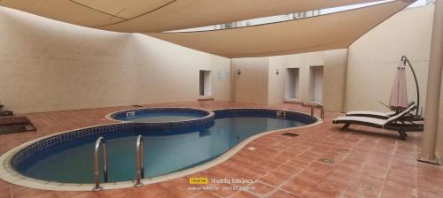 una grande piscina in un edificio con soffitto di SADARA HOTELS APARTMENTS a Sohar