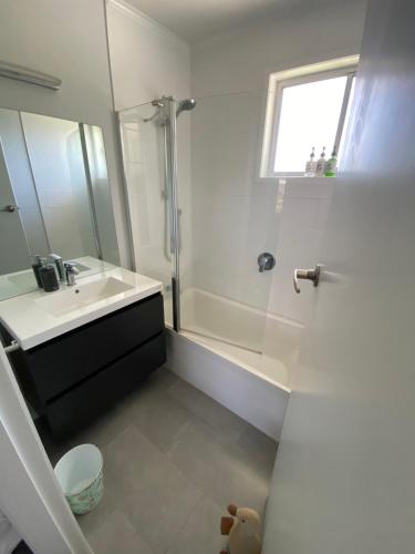 a white bathroom with a sink and a shower at Sunny Inn Tawavale in Rotorua