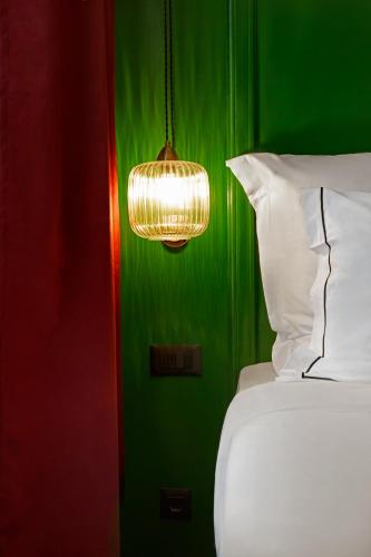 a bedroom with a green wall with a bed and a light at SoHo Athinas 60 in Athens