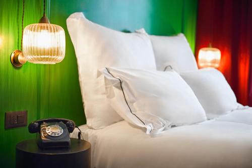 a bed with a clock on a table with a lamp at SoHo Athinas 60 in Athens