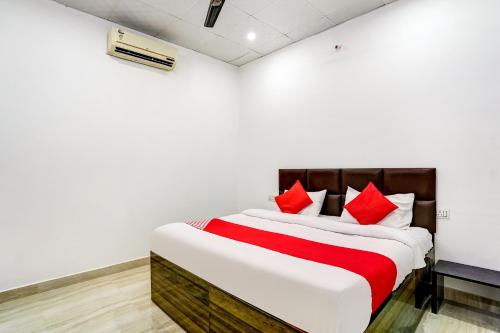 a bedroom with a large bed with red pillows at Flagship Hotel Aashirvad in Faridabad