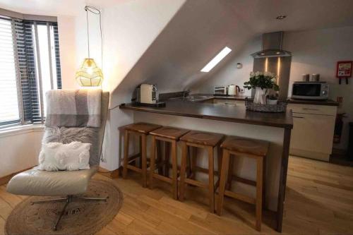 a kitchen with a counter and a chair in a room at Creel Cottage (No. 4) in Arbroath