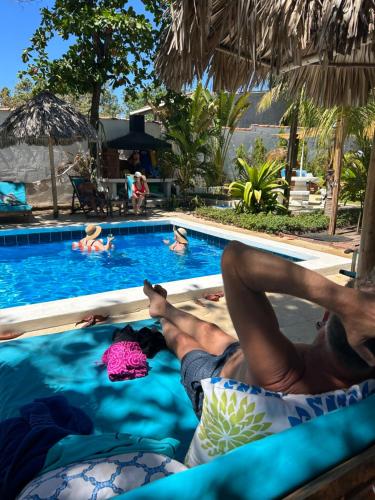 a man laying on a bed next to a swimming pool at Hotel Tranquilo in Las Peñitas