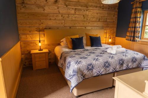 a bedroom with a bed with a wooden wall at Blazing Donkey Country Hotel in Sandwich