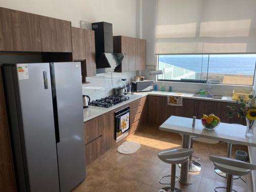 een keuken met een koelkast en een tafel met stoelen bij Casa de Playa moderna in Lima