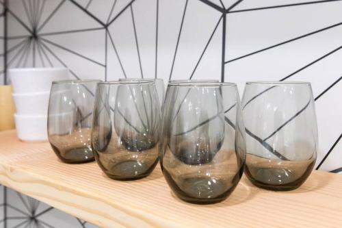 four empty wine glasses sitting on a wooden table at Stylish Casita min from the beach ! in San Juan Capistrano