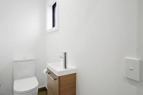 a white bathroom with a toilet and a sink at Wanaka Riverside serviced apartments by BCR Stays in Albert Town