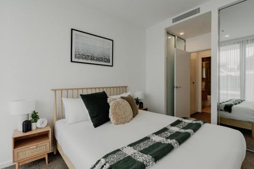 a bedroom with a large white bed and a mirror at Comfy 1-Bed Apt with Courtyard, Gym, BBQ & Parking in Kingston 