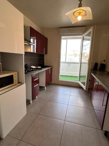 une cuisine avec des armoires rouges et une grande fenêtre dans l'établissement Logement gare Saint Charles ideal famille, à Marseille