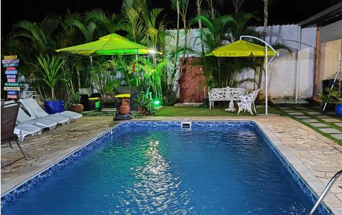 a swimming pool with two umbrellas in a yard at Chácara Flores de Maio in Atibaia