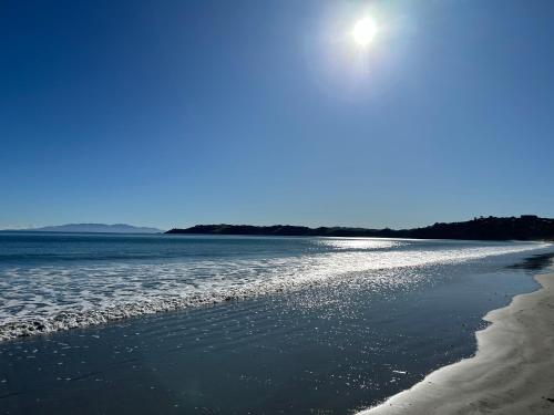 uma praia com o sol brilhando sobre a água em Whisper Cottage em Onetangi