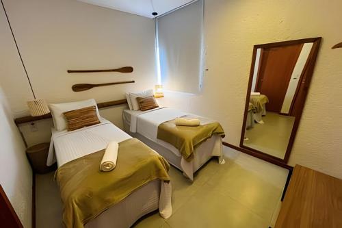 Habitación con 2 camas y espejo. en Refúgio em Condomínio Resort na Rota dos Milagres, en Porto de Pedras
