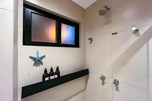 uma casa de banho com um chuveiro, uma janela e garrafas de vinho em Refúgio em Condomínio Resort na Rota dos Milagres em Porto de Pedras