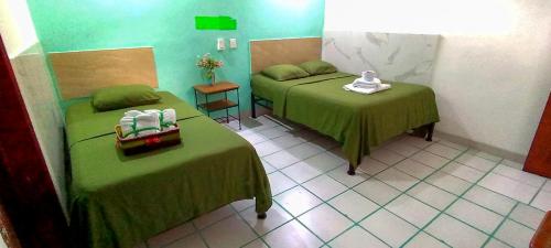 a room with two beds with green sheets at Posada Nacha`n - Ka`an in Palenque