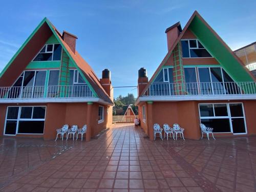 a building with white chairs in front of it at Cabañas y Habitaciones El Malecón in Zirahuén