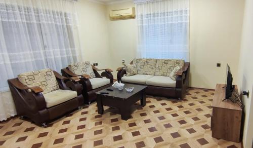 a living room with chairs and a tv and a table at Pink Quest House in Lankaran