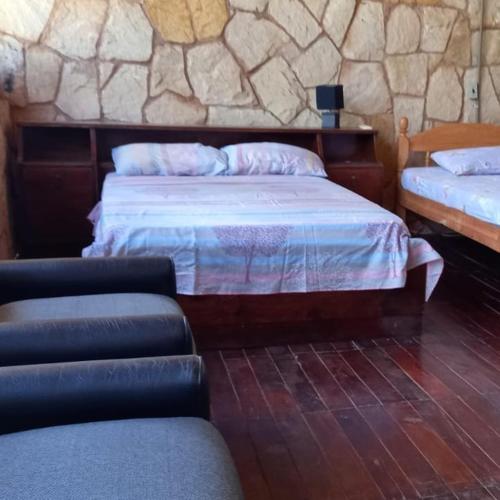 a bedroom with two beds and a stone wall at Cabaña Las Palmeras in San Bernardino