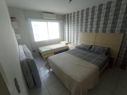a small bedroom with a bed and a window at Apto espaçoso uma quadra do mar com garagem in Balneário Camboriú
