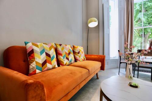 an orange couch with colorful pillows in a living room at Charming 1 Bed Flat Portobello in London