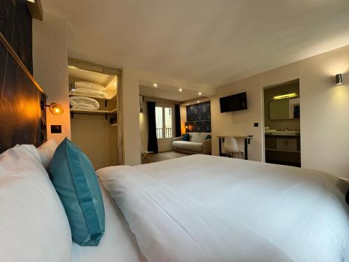 sypialnia z dużym białym łóżkiem z niebieskimi poduszkami w obiekcie Hotel Nation Montmartre w Paryżu