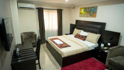 a bedroom with a bed and a chair and a television at The Lodge-Stack By Kabachi in Lagos