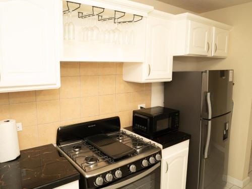 a kitchen with white cabinets and a stove and a microwave at Sunset Cove Barbados in Christ Church