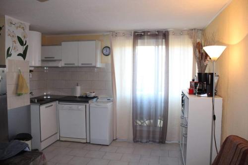 Elle comprend une petite cuisine avec des appareils électroménagers blancs et une fenêtre. dans l'établissement Studio cap Agde, au Cap d'Agde