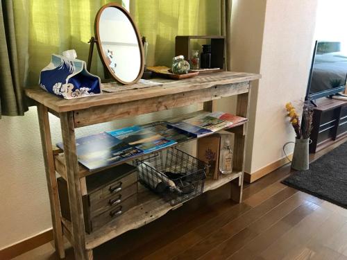 een houten console tafel met een spiegel en boeken bij Tipy records room in Odawara