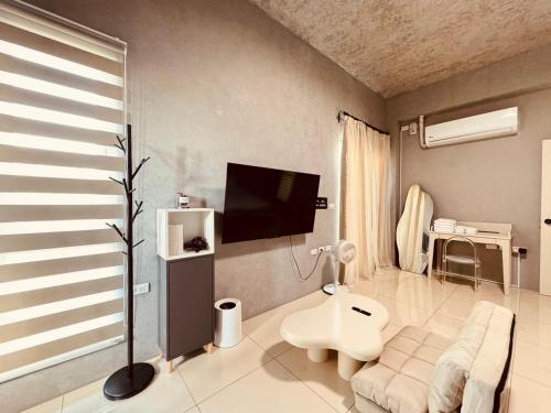 a living room with a couch and a tv on the wall at Xu Xu Homestay in Chiayi City
