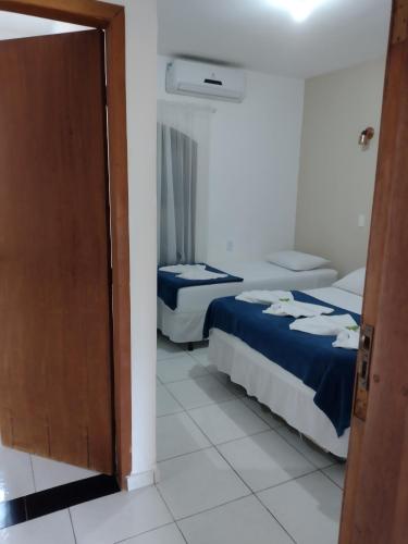 a bedroom with two beds and a door open at Hotel Portal da Praia in Barequeçaba