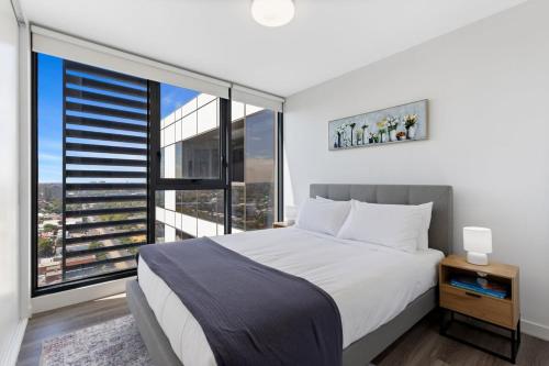 um quarto com uma cama grande e uma janela grande em Elegant Inner-West 2-Bed with City Views & Pool em Melbourne