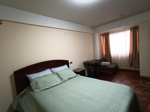 a bedroom with a bed with green sheets and a window at Apartamento cómodo in Potosí