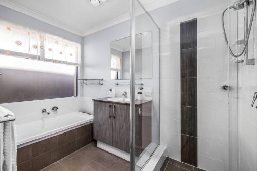 uma casa de banho com uma banheira, um lavatório e um chuveiro em Halls Head Beach Haven em Mandurah