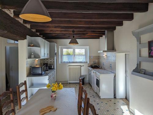 une cuisine avec une table et des chaises dans une pièce dans l'établissement Gîte en Sologne avec Jardin Privatif, Proche Orléans et Châteaux de la Loire - FR-1-590-54, à Jouy-le-Potier