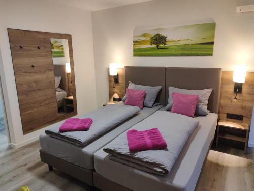 a bedroom with two beds with pink pillows at Hotel Gästehaus Stock Zimmer Bäumle in Friedrichshafen
