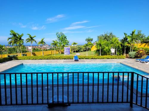 a swimming pool with a fence and palm trees at Island Hideaway in Falmouth
