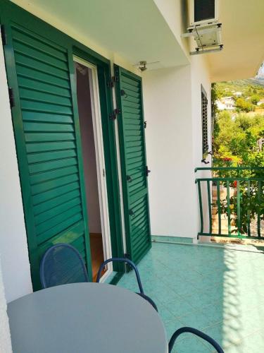 a table and chairs on a balcony with green doors at Apartments by the sea Brist, Makarska - 22463 in Podaca