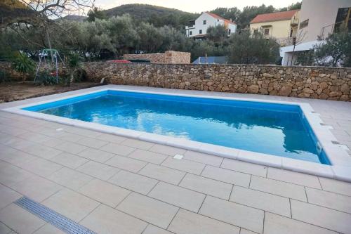 einen Pool in einem Garten mit einer Steinmauer in der Unterkunft Apartments with a swimming pool Stari Grad, Hvar - 4015 in Stari Grad
