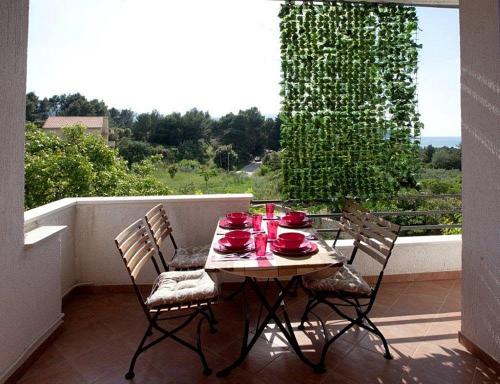a table on a balcony with red dishes on it at Apartments with a swimming pool Stari Grad, Hvar - 4015 in Stari Grad