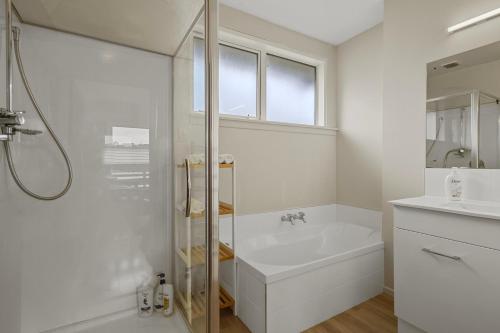 a white bathroom with a shower and a sink at Matipo Retreat - Christchurch Holiday Home in Christchurch