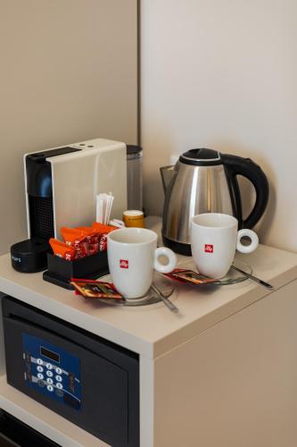 two coffee cups and a coffee pot on a microwave at AlbaDea Déco&Jacuzzi in Rome