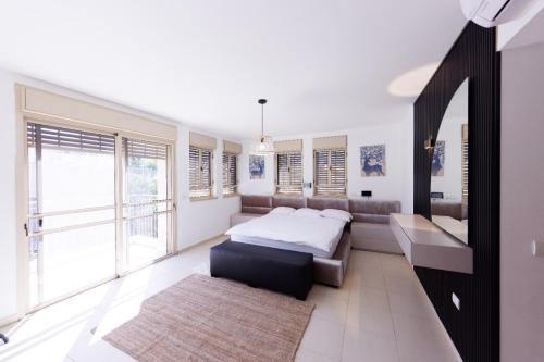a bedroom with a bed and a couch and windows at Five Stars Villa09 in Hod HaSharon